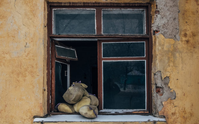 Shabby grungy cracked wall, broken window, old toy dragon on the
